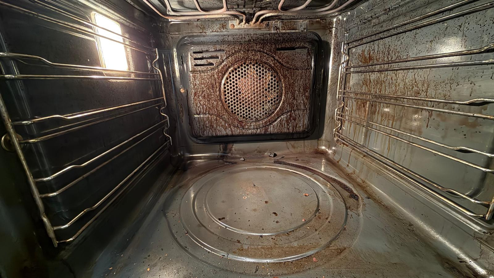 Oven interior showing grease buildup around the fan and base before cleaning