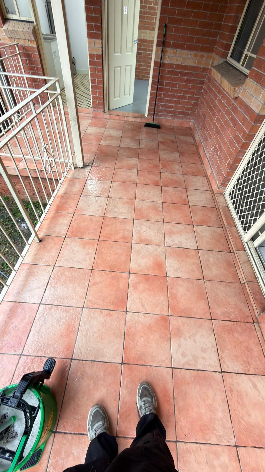 Tiled outdoor patio with cleaning equipment beside the entrance